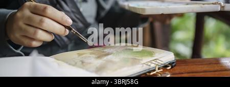 Student im Kunststudio. Hand haltender Künstler Pinsel mischen FarbÖlgemälde auf Palette Kunst Kreativität und Menschen Konzept Stockfoto