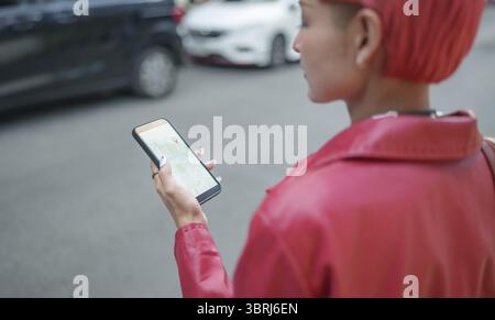 Traveler Gen z Mädchen Ledermode mit Punk asiatische Frau Tourist in der Stadt Straße Suche Standort in Karte Anwendung Online Smartphone mit GPS na Stockfoto