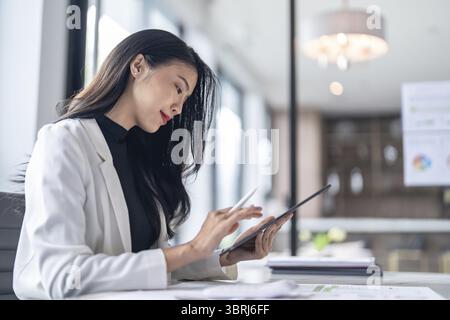 Schöner asiatischer Arzt Bildung Beruf Arzt in weiß Uniform Kleid Mantel professioneller Arzt mit Tablette am Seminar oder Krankenhaus Wellness Stockfoto