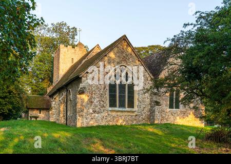 Die Steinkirche St. Augustinus aus dem 13. Jahrhundert im Dorf Snave in Kent in der frühen goldenen Stunde. Chorfenster und Kirchturm. Stockfoto