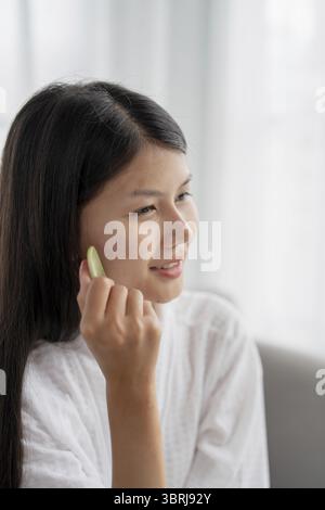Tägliche Schönheit Routine Asiatische Frau Selbstpflege Gua Sha Gesichtsmassage traditionelle Medizin Gua Sha Quarzstein Kosmetik natürliche Trend Stockfoto