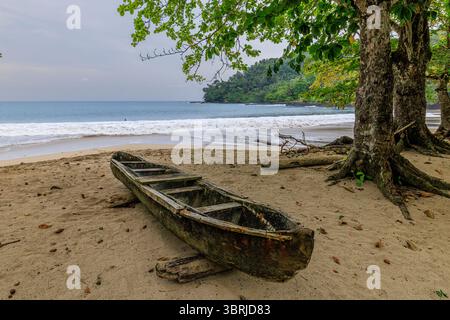 Ein hölzernes Kanu, das von Einheimischen zum Angeln genutzt wird, zog an einem idyllischen Sandstrand an der atlantikküste der tropischen Insel sao Tome an Stockfoto