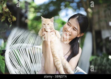 Lächelnde schöne asiatische junge Frau mit Ingwerkatze Wellness-Porträt Glück im Freien Stockfoto