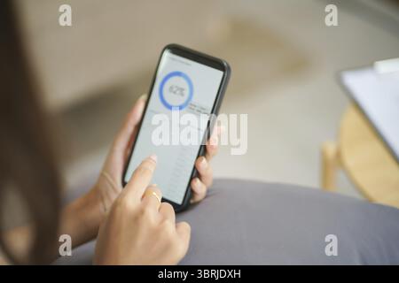 Frau überprüft Finanzdaten auf Smartphone menschliche Hand hält Handy, das von zu Hause aus arbeitet Stockfoto
