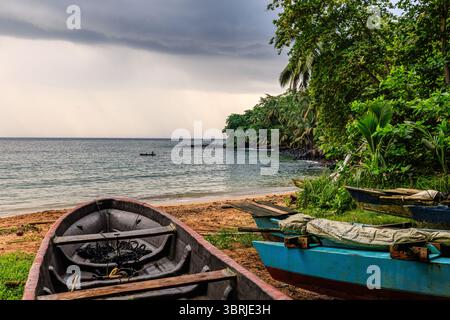 Farbenfrohe Holzfischboote an einem Sandstrand in einer ruhigen Bucht mit üppiger Vegetation im tropischen Paradies principe Stockfoto