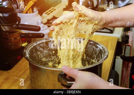 Der Teig durch weibliche Hände für die Herstellung von Brot auf hölzernen Tisch Stockfoto