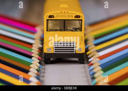 Buntstifte und Spielzeuggelber Schulbus, zurück zur Schule Stockfoto