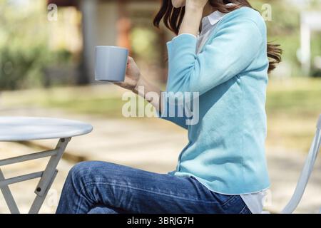 Frauenhände halten eine Tasse Kaffee im Park Stockfoto