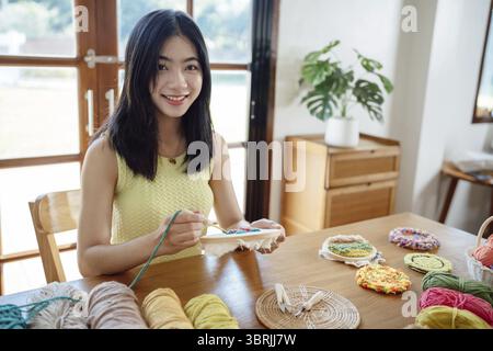 Stanznadel. Asiatische Frau, die handgemachtes Hobby-Stricken in der Atelierwerkstatt herstellt. Designer-Arbeitsplatz Handgefertigtes Bastelprojekt DIY Stickkonzept Stockfoto