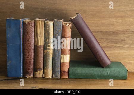 Stapel alter grungy Bücher auf hölzernem Hintergrund. Hardcover alte und zerrissene Bücher auf einem Tisch Stockfoto