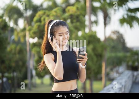 Happy Active Healthy asian Woman hört Musik mit Kopfhörern für geistige Gesundheit Hören von Audio für Laufen Inspiration Stockfoto