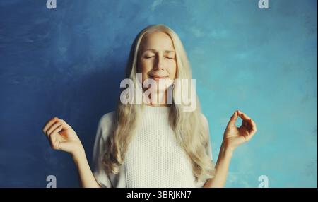 Ruhig entspannt gesund reife Frau meditiert, üben Yoga Übungen, mit geschlossenen Augen, Stress lindern zu Hause Stockfoto