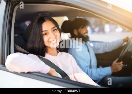 Junge Indianerin lächelt aus dem Fenster, während ein Mann Auto fährt Stockfoto