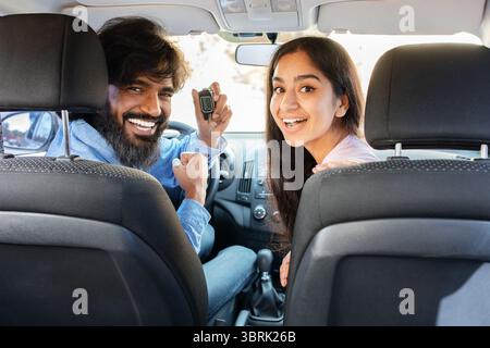 Aufgeregt indisches Paar zeigt Autoschlüssel und lächelt auf den Vordersitzen Stockfoto