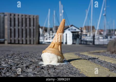 Ein heruntergefallener Eiskegel schmilzt auf einer sonnigen Straße Stockfoto