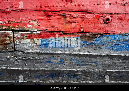 Strukturierte Holzoberfläche mit verwitterter, abblätternder Farbe in Rot und Blau Stockfoto