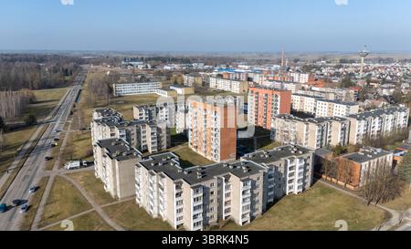 Aus der Vogelperspektive auf ein Wohngebiet mit mehreren Wohngebäuden, Grünflächen und einer Straße. Die Landschaft umfasst eine Mischung aus städtischen und ländlichen Elementen Stockfoto