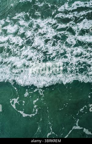 Abstrakte Luftaufnahme des wirbelnden Meeresschaums auf tiefgrünem Wasser Stockfoto