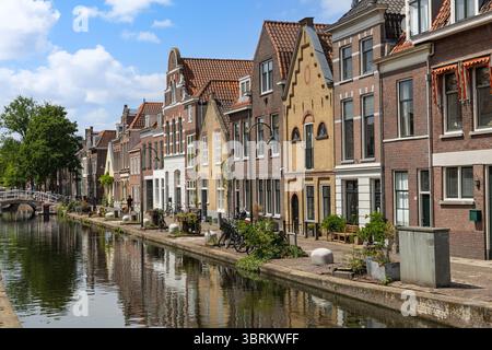 Eine malerische Kanalszene in Gouda, Niederlande, mit historischen niederländischen Häusern mit klassischen Giebeln, die sich wunderbar im ruhigen Wasser spiegeln. Stockfoto
