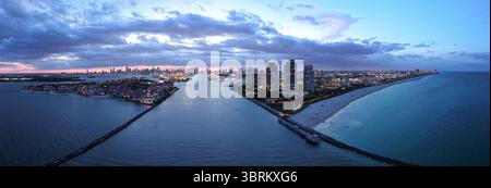 Aus der Vogelperspektive auf die nächtliche Küste von South Beach. Miami Skyline mit tropischem blauem Wasser Panorama. Panorama über die Wolkenkratzer von Miami in der Abenddämmerung. Stockfoto