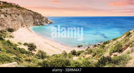 Atemberaubende Küstenlandschaft mit Sandstrand, dramatischen felsigen Klippen und kristallklarem türkisfarbenem Wasser in Cleopatra Cove, Cesme, Turkiye Stockfoto