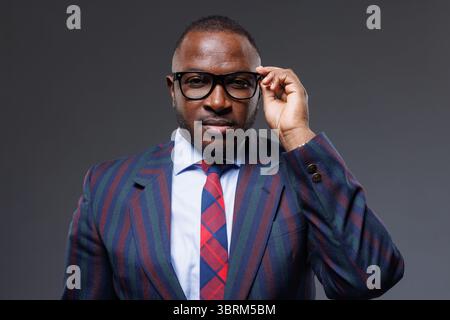 Selbstbewusster afrikanischer Geschäftsmann in trendiger Brille und elegantem Anzug, der Stil und Führung in der Geschäftswelt zeigt Stockfoto
