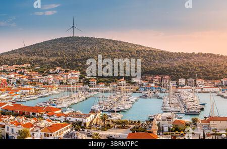 28. April 2025, Cesme, Turkiye: Panoramablick auf Hafen, historische Burg, Windturbine und charmante Stadt bei Sonnenuntergang Stockfoto