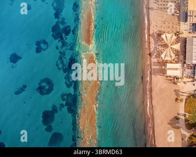 Atemberaubende Luftperspektive, die die lebhaften Farben von türkisfarbenem Wasser, goldenem Sand und Sonnenschirmen in einem luxuriösen Resort einfangen Stockfoto