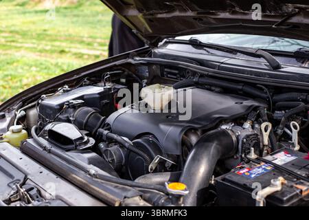 Pkw-Motor mit offener Motorhaube, Motorkomponenten und Trichter zum Einfüllen von Motoröl. Stockfoto