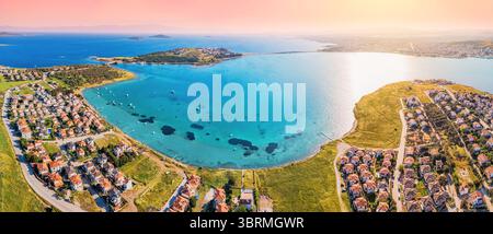 Atemberaubender Panoramablick auf Ayvalik, Türkei, bei Sonnenuntergang, mit türkisfarbenem Wasser, modernen Häusern, und eine ruhige Küstenlandschaft Stockfoto