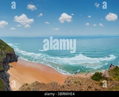 Sandstrand mit felsigen Bergrücken trübes Wetter Aussicht auf Sommer Atlantic an der felsigen Küste (Costa Vicentina, Algarve, Portugal). Und Ocean Surf Wellen. Stockfoto