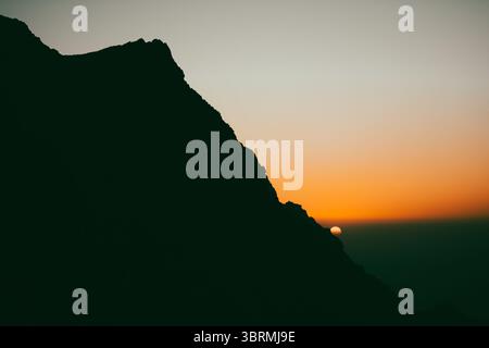 Epischer Blick auf den Sonnenuntergang von der Bergspitze im Winter, Bergkugel-Silhouette bei Sonnenuntergang Stockfoto