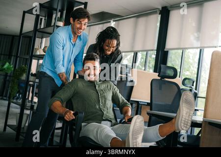 Begeisterte verschiedene Mitarbeiter lachen lustige Aktivitäten in der Pause, kreative freundliche Mitarbeiter Stockfoto