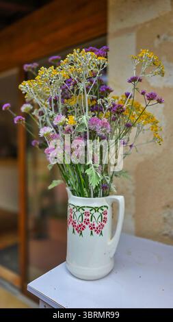 Niedlicher Blumenstrauß in Gelb- und Fliederfarben in einem weißen Keramikkrug Stockfoto