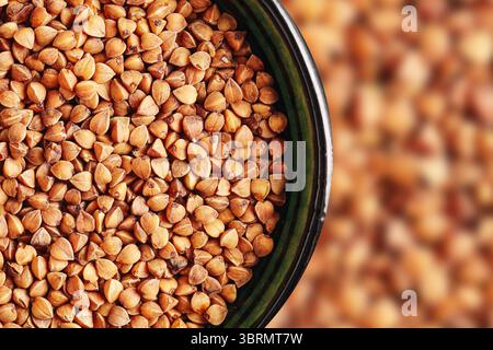 Buchweizengrieß in grüner Schüssel-Textur. Gesunde glutenfreie Kornnahmebildung. Trockene Bio-Vollkost. Natürliche rustikale Zutat zum Kochen. Stockfoto