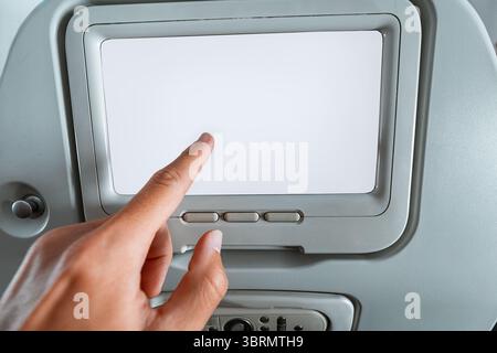 Nahaufnahme der Hand mit leerem Touchscreen auf dem Flugzeugsitz für personalisierte Unterhaltung während der Reise Stockfoto