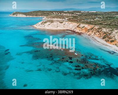 Atemberaubender Blick aus der Vogelperspektive auf türkisfarbenes kristallklares Wasser, das sanft die felsige Küste wäscht und die Schönheit der Natur zeigt Stockfoto