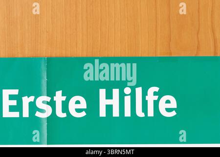 Eine Nahaufnahme zeigt die Oberseite eines Posters „erste Hilfe“ mit Holzmaserung. Das Poster ist gefaltet. Stockfoto