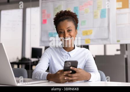 Frau, die das Smartphone hält und in die Kamera schaut Stockfoto