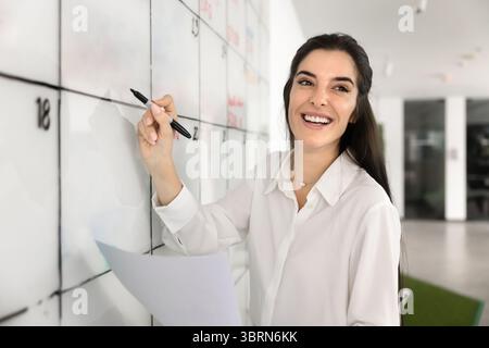 Frau, die Termine, Planungsaufgaben oder Meetings im Coworking Office vornimmt Stockfoto