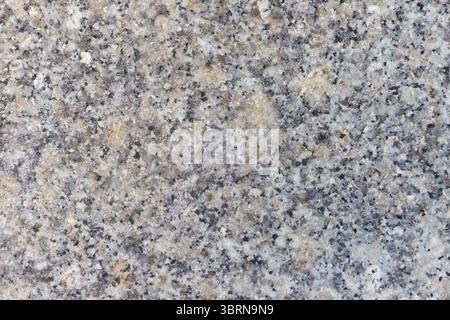 Nahaufnahme einer gesprenkelten Granitoberfläche mit schwarzen, grauen und beigen Mineralkörnern. Stockfoto