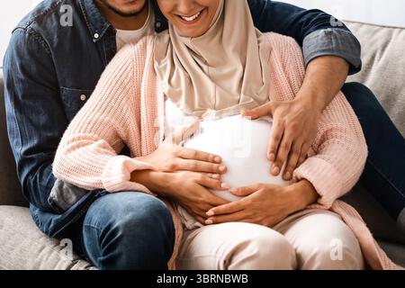 Glücklich Schwanger Muslim Paar Entspannen Auf Couch Zu Hause Stockfoto