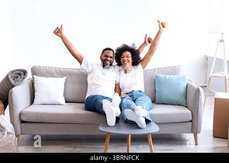 Schwarze Ehepartner Feiern Umzug Tag In New House, Gestikuling Thumbs-Up Stockfoto