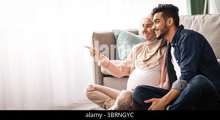 Porträt Eines Glücklichen Schwangeren Paar Aus Dem Nahen Osten, Das Sich Auf Dem Boden Ausruht Wohnzimmer Stockfoto