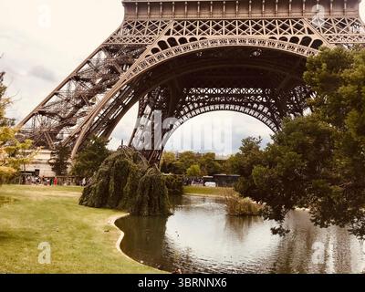 Am Fuße des Eiffelturms mit Reflektionen und Gartenteich in Paris Stockfoto