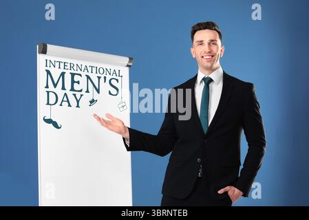 Internationale Karte für Herren. Glücklicher Mann, der auf das Brett vor blauem Hintergrund zeigt Stockfoto