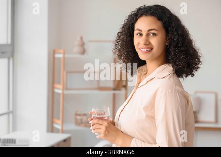 Junge afroamerikanische Frau mit einem Glas Wasser zu Hause Stockfoto