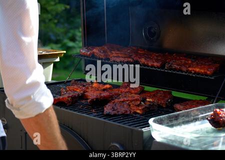 Barbecue-Rippchen brutzeln auf einem Räuchergrill im Freien während eines Sommergartens Stockfoto
