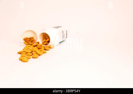Die Prescripton-Flasche liegt auf der Seite mit einem Stapel verschütteter Tabletten davor. Ebene Ansicht in die Oberseite des Containers. Stockfoto
