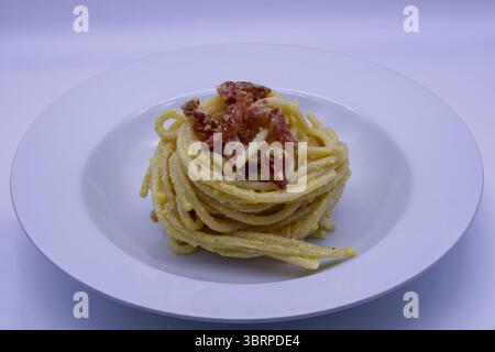 Cremige traditionelle italienische Pasta Carbonara mit knusprigem Speck und Pecorino romano Käse, Pfeffer, serviert auf einem weißen Teller. Stockfoto